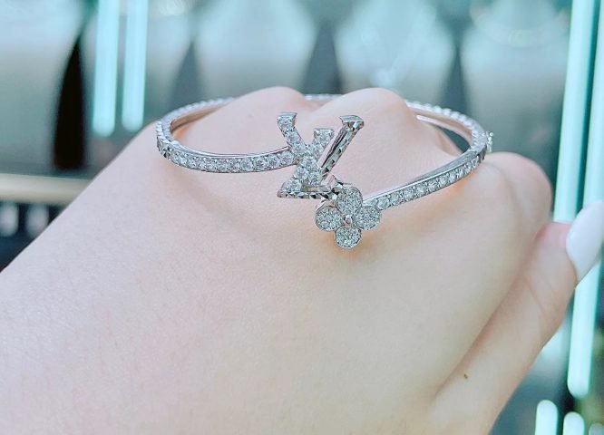 Vòng tay Louis Vuitton cỏ 4 lá đính đá lấp lánh trên nền trắng, thể hiện sự sang trọng và may mắn.