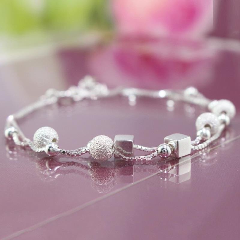 Cổ tay người phụ nữ đeo nhiều chiếc lắc tay có màu sắc khác nhau, thể hiện cách chọn lắc tay theo màu da