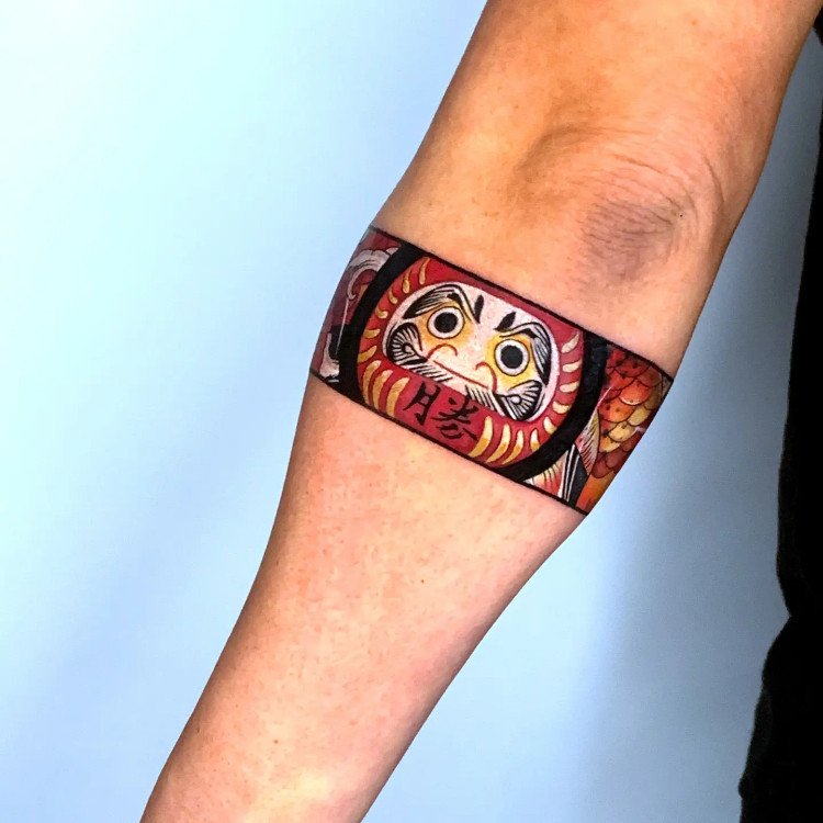 Hình xăm vòng tay nhật cổ đen trắng Daruma với biểu cảm kiên cường
