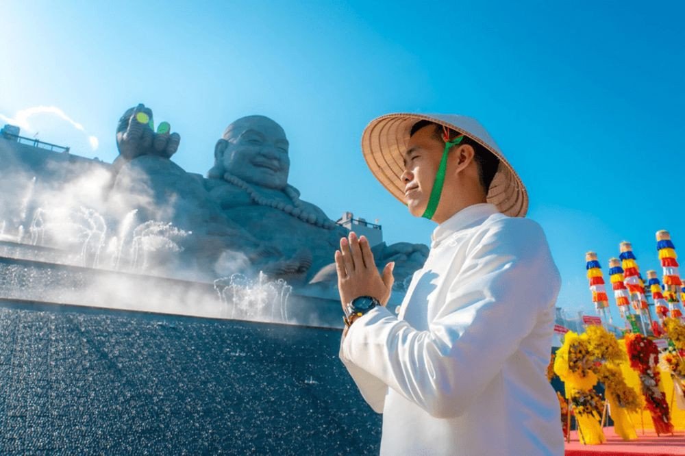 Khách hành hương thành tâm khấn nguyện bình an, tài lộc trước tượng Phật Di Lặc