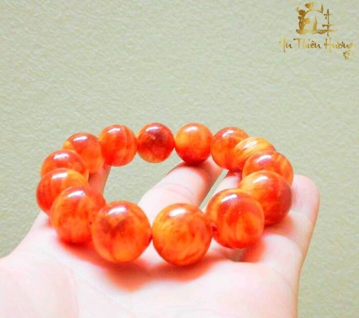 Vòng tay gỗ huyết long đỏ cam với vân gỗ độc đáo, thu hút tài lộc cho người mệnh Hỏa nam.