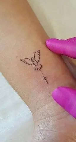 Tatuaje-de-cruz-en-la-muñeca-y-paloma